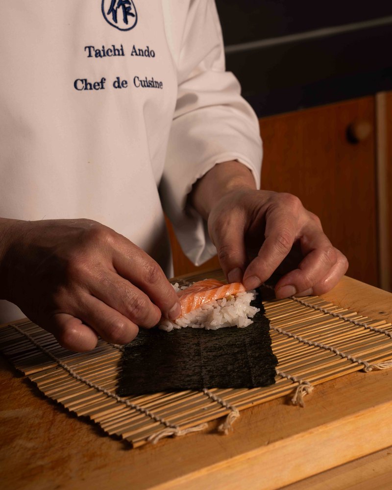 The chef rolling maki at the counter — Saku