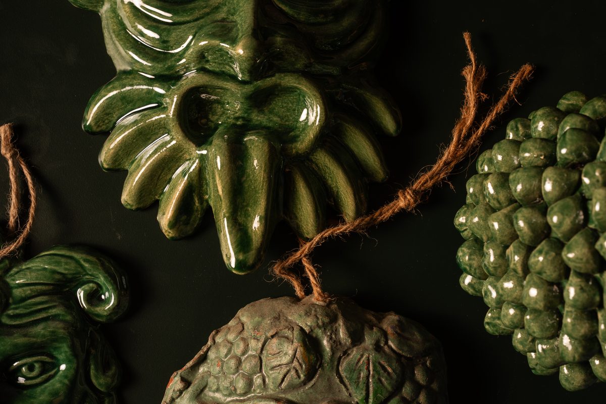 Masques en céramique verte au mur de Nonno San